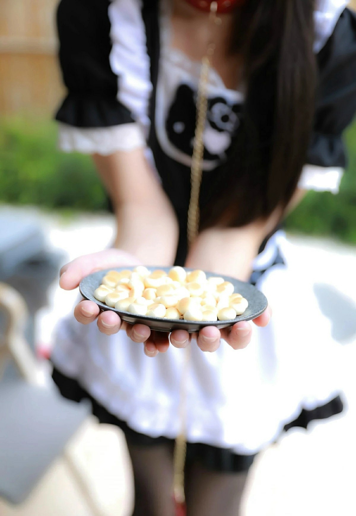女仆装少女双手端着一盘奶香味小饼干